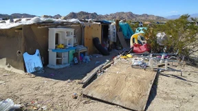 Eltern halten ihre drei Kinder in Holzverschlag