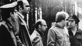 Ortstermin: Der Serienmörder Joachim Kroll (Mitte) wird 1980 von Kriminalbeamten, Richtern und Sicherheitskräften in einen Wald bei Breitscheid geführt, wo er zehn Jahre zuvor die 13 Jahre alte Jutta Rahn ermordet hatte.