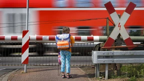 Lehrerinnen führen Schüler durch geschlossene Bahnschranken