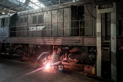 Echte Handarbeit: Für die Eisenbahn arbeiten 170.000 Menschen. Zwei von ihnen schweißen die beschädigte Lok mit dem grau-roten Tarnmuster.