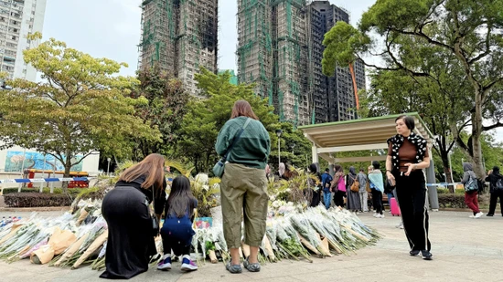 Menschen in Hongkong legen am Sonntag vor den Brandruinen Blumen nieder