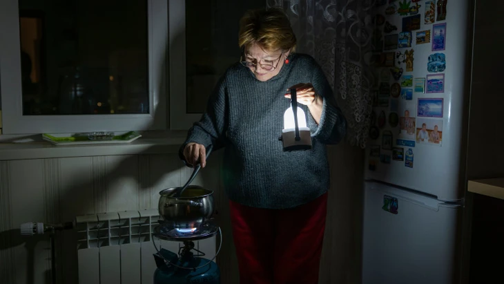 Eine Frau in Kiew kocht während eines Stromausfalls infolge eines russischen Angriffs.  +++