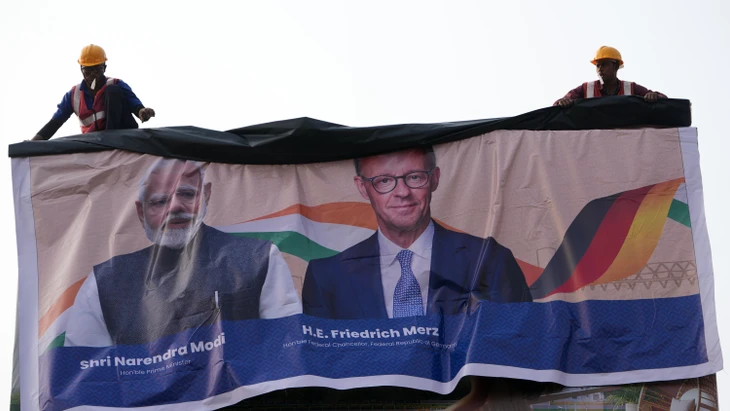 Willkommen in Indien: Arbeiter montieren ein Plakat des indischen Premierministers Narendra Modi und des deutschen Bundeskanzlers Friedrich Merz (CDU).