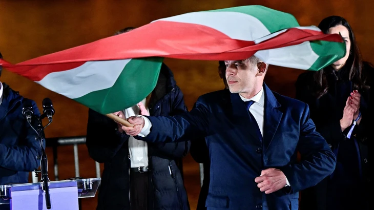 Wahlsieger Péter Magyar schwenkt am Abend in Budapest eine ungarische Flagge.