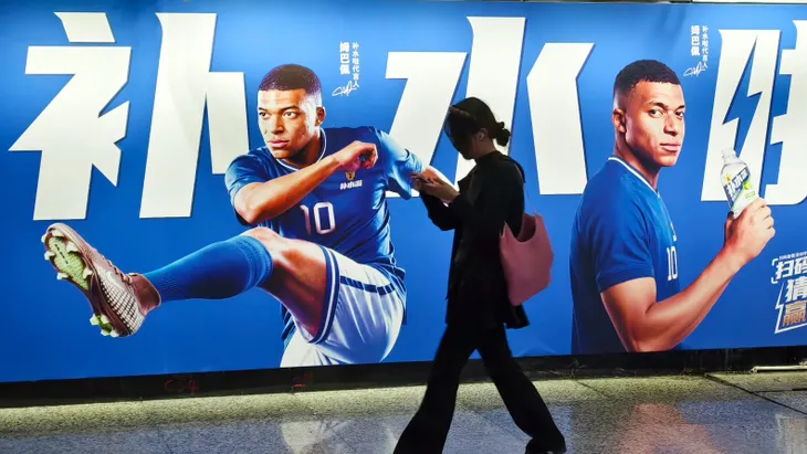 Eine Frau vor einer Werbung mit Mbappé in Shanghai