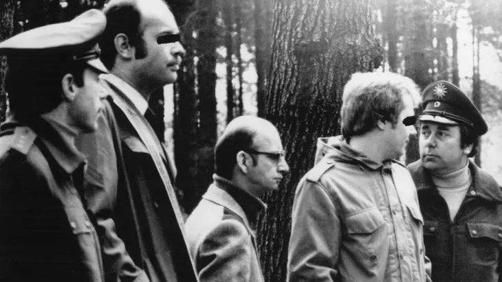 Ortstermin: Der Serienmörder Joachim Kroll (Mitte) wird 1980 von Kriminalbeamten, Richtern und Sicherheitskräften in einen Wald bei Breitscheid geführt, wo er zehn Jahre zuvor die 13 Jahre alte Jutta Rahn ermordet hatte.
