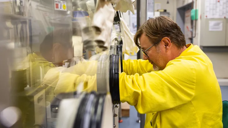 Am Karlsruher Institut für Technologie ist ein Mitarbeiter an einer Glovebox für die physikalisch-chemische Untersuchung von Brutmaterialien für die Tritiumproduktion zu sehen.