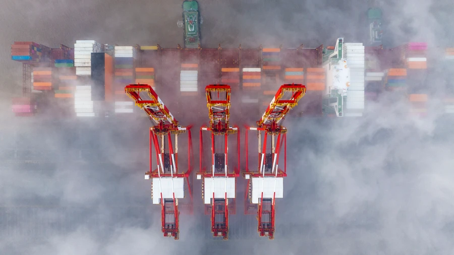 Kräne und ein Containerschiff im Hafen von Shanghai