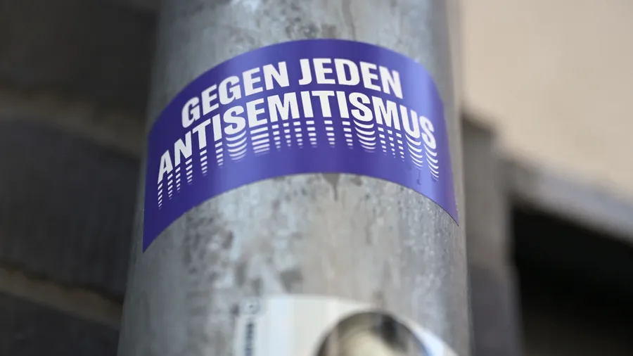 Ein Sticker mit der Aufschrift „Gegen jeden Antisemitismus“ hängt an einem Laternenmast in Berlin.