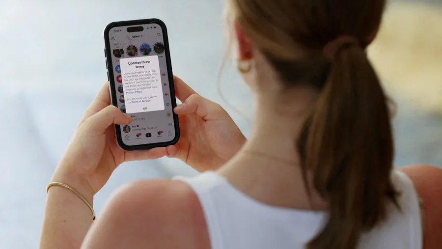 Eine Jugendliche posiert mit einem Mobiltelefon, auf dessen Display eine Nachricht von TikTok zu sehen ist, während in Sydney ein Gesetz in Kraft tritt, das soziale Medien für Nutzer unter 16 Jahren in Australien verbietet.