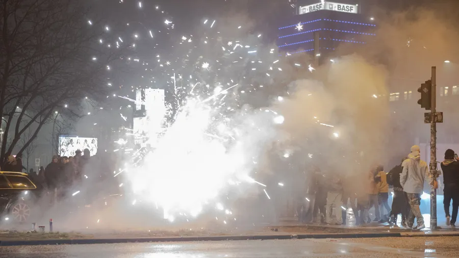 Wichtige Tradition oder gefährliches Spektakel? Böller und Raketen steigen an einem Silvesterabend in Berlin in die Luft, während Passanten vorbeilaufen.