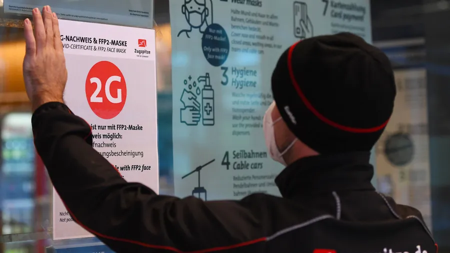 Bayern: Ein Mitarbeiter der Zugspitzbahn klebt einen 2G Hinweis an die Eingangstür der Talstation.