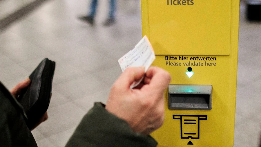 Ein Fahrschein der Berliner Verkehrsbetriebe wird vor einen Entwerter gehalten.