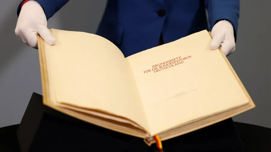 Eine Mitarbeiterin des Parlamentsarchivs des Deutschen Bundestages zeigt Seiten des Originalbuchs des Grundgesetzes.