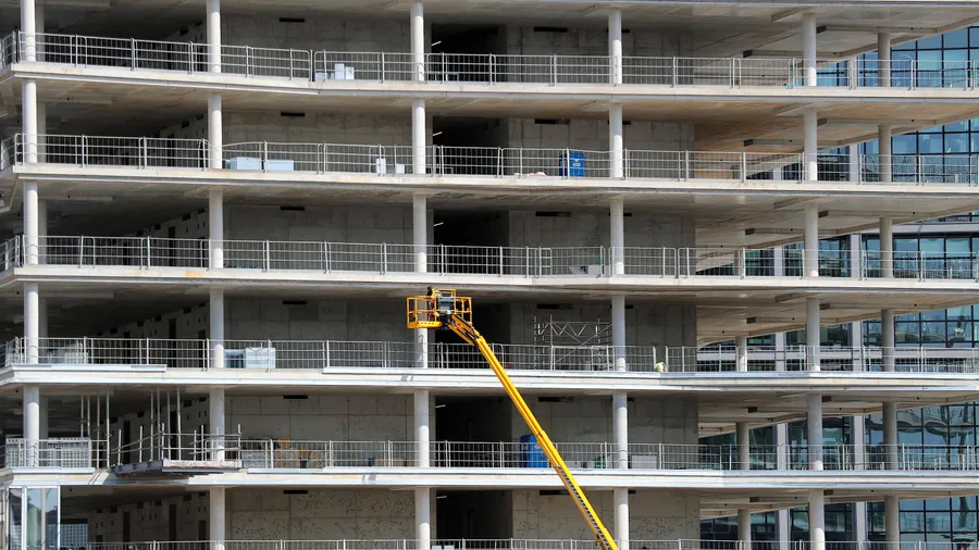 Arbeiter montieren von einer Hebebühne aus Teile an einem Neubau in Berlin (Archivbild).