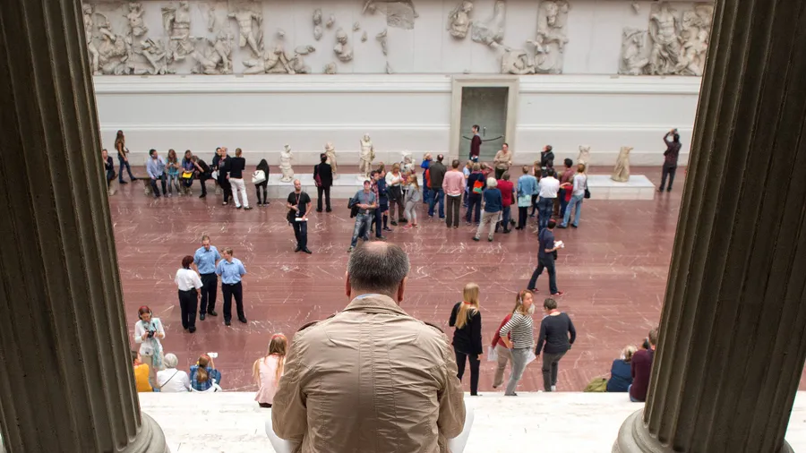 Besucher schauen die Fresken des Pergamonaltars in Berlin an.