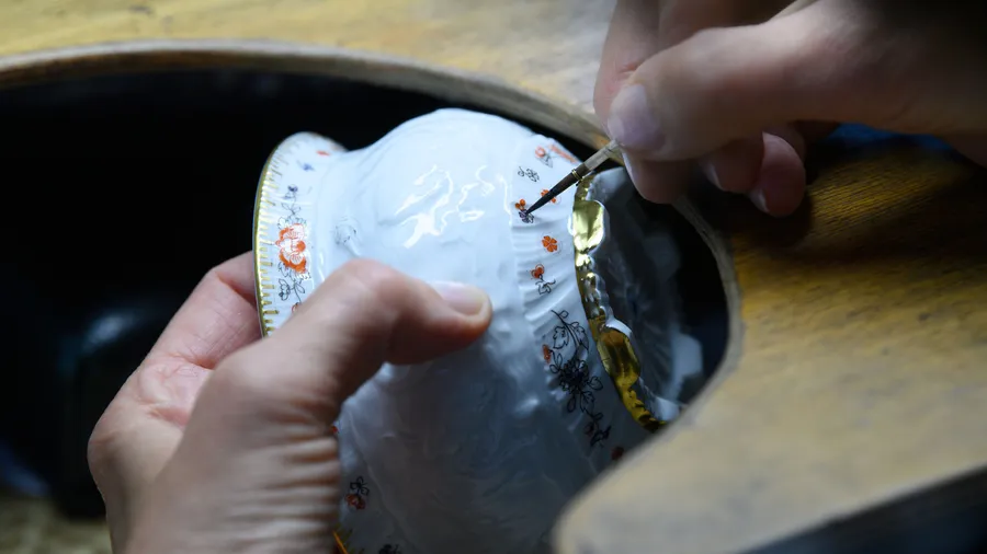 Eine Mitarbeiterin in der Aufglasurmalerei der Staatlichen Porzellan-Manufaktur Meissen bemalt eine Zuckerdose.