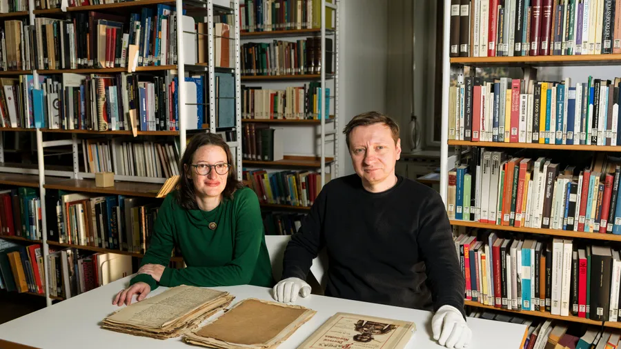 Recherchearbeit: Provenienzforscher Josefine Neef und Godwin Kornes mit Archivmaterial und dem Studienband „Unter den Papua’s“ (1899) von Bernhard Hagen in der Bibliothek des Weltkulturen Museums