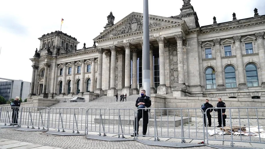 Polizeibeamte sichern hinter Absperrzäunen das Reichstagsgebäude.