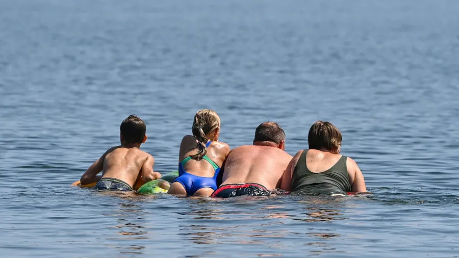 Eine Familie schwimmt auf einer Luftmatratze in einem See bei Storkow