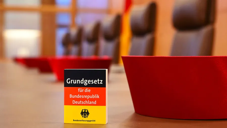 Im Sitzungssaal des Bundesverfassungsgerichts liegen die Barette der Richter, sowie das Grundgesetz für die Bundesrepublik Deutschland.