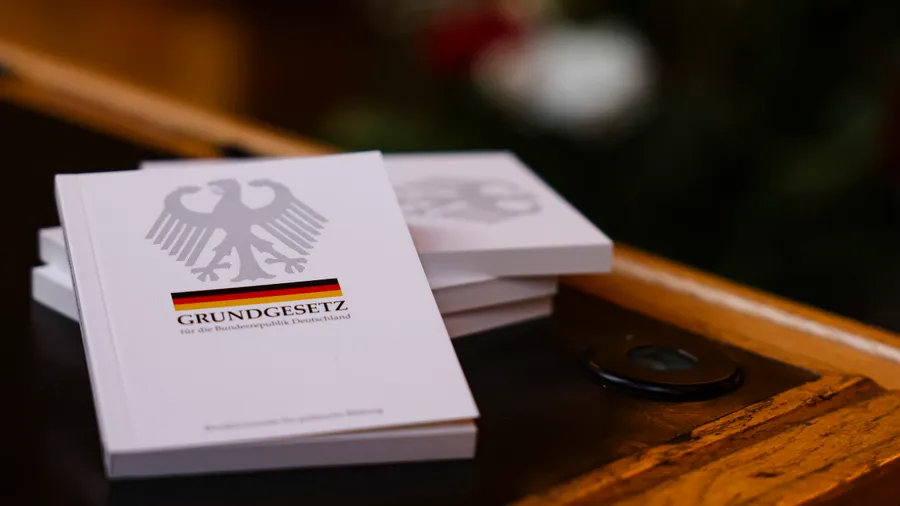 Vier Bücher mit dem Grundgesetz liegen während einer Einbürgerungsfeier auf einem Tisch.