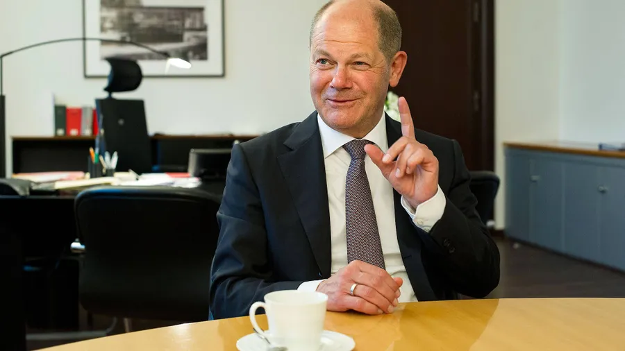 Der heutige Bundeskanzler Olaf Scholz in seinem Büro als Bundesfinanzminister. Im Hintergrund ist eines der Bilder vom deutschen Pavillon für die Weltausstellung 1958 in Brüssel zu erkennen.