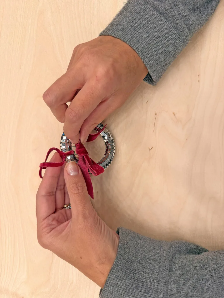 Schritt 5: Schmales Samtband doppelt legen und auf die gewünschte Länge zum Aufhängen zuschneiden. Durch den Ring ziehen, feste Knoten an Ring und Schlaufe ziehen, Öse an der Schleife durch den hinteren Teil des Knotens am Ring ziehen und mit der Zange schließen.