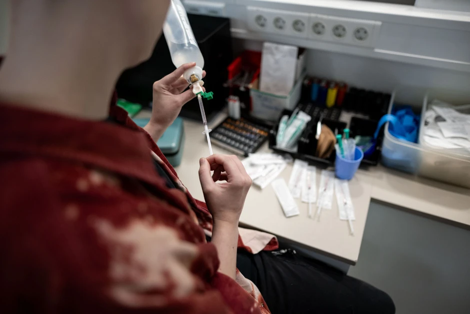 Eine Mitarbeiterin bereitet Spritzen mit Kochsalzlösung für den späteren Gebrauch vor.