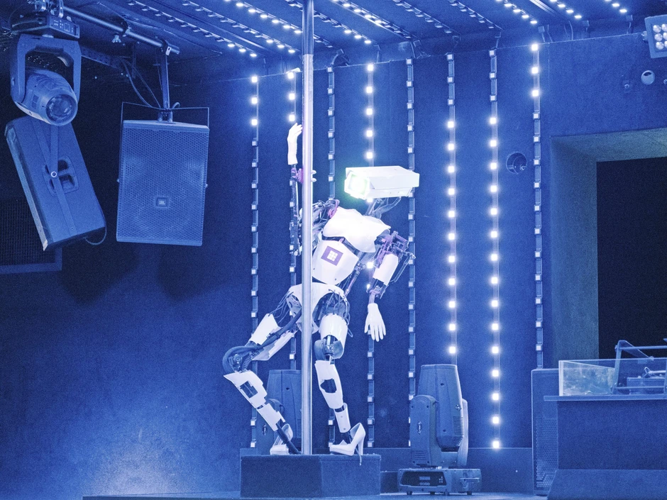 An einer der Tanzflächen in der Großraumdisko tanzen Roboter um Stangen.