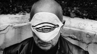 Durch das Zyklopenauge: Jörg Immendorff bedeckt mit einem Mundschutz, der FFP2-Maske nicht unähnlich, sein Gesicht. Durch das Zyklopenauge: Jörg Immendorff bedeckt mit einem Mundschutz, der FFP2-Maske nicht unähnlich, sein Gesicht.