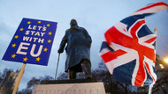 Brexit-Gegner halten ein Schild und eine Fahne bei einer Kundgebung vor einer Statue von Winston Churchill.