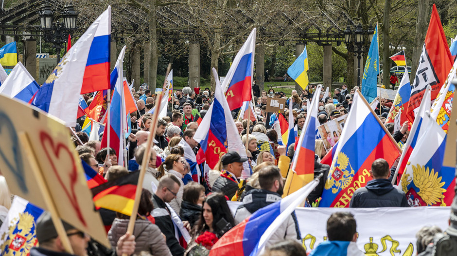 Vista de una manifestación a favor de Rusia en Alemania con banderas y presencia policial en una plaza urbana