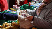 Die Bananen schon etwas braun, die Birnen mit Druckstellen: Eine Mitarbeiterin füllt den Beutel einer Tafel-Kundin im Berliner Osten mit vom Supermarkt aussortierten Lebensmitteln.