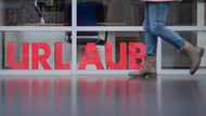 Großbuchstaben bilden in dem Schaufenster eines geschlossenen Reisebüros im Flughafen Dresden das Wort „Urlaub“. 