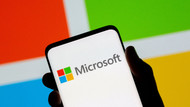 Ein Mobiltelefon vor dem Logo von der Firma Microsoft Ein Mobiltelefon vor dem Logo von der Firma Microsoft