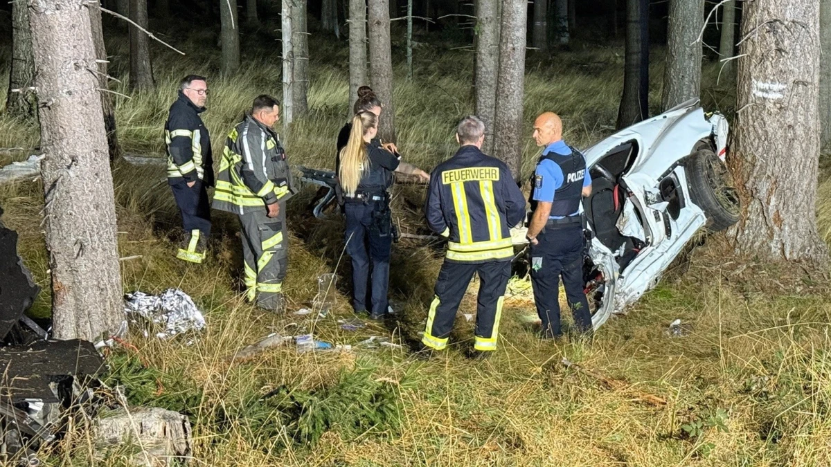 Rettungskräfte stehen nach der Bergung der zwei Insassen vor den Trümmern des Unfallfahrzeugs. - dpa