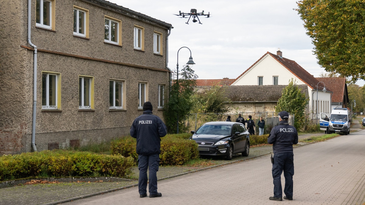 Polizisten stehen am Dienstag vor einem Grundstück in Tauche (Landkreis Oder-Spree) und starten eine Drohne. - dpa
