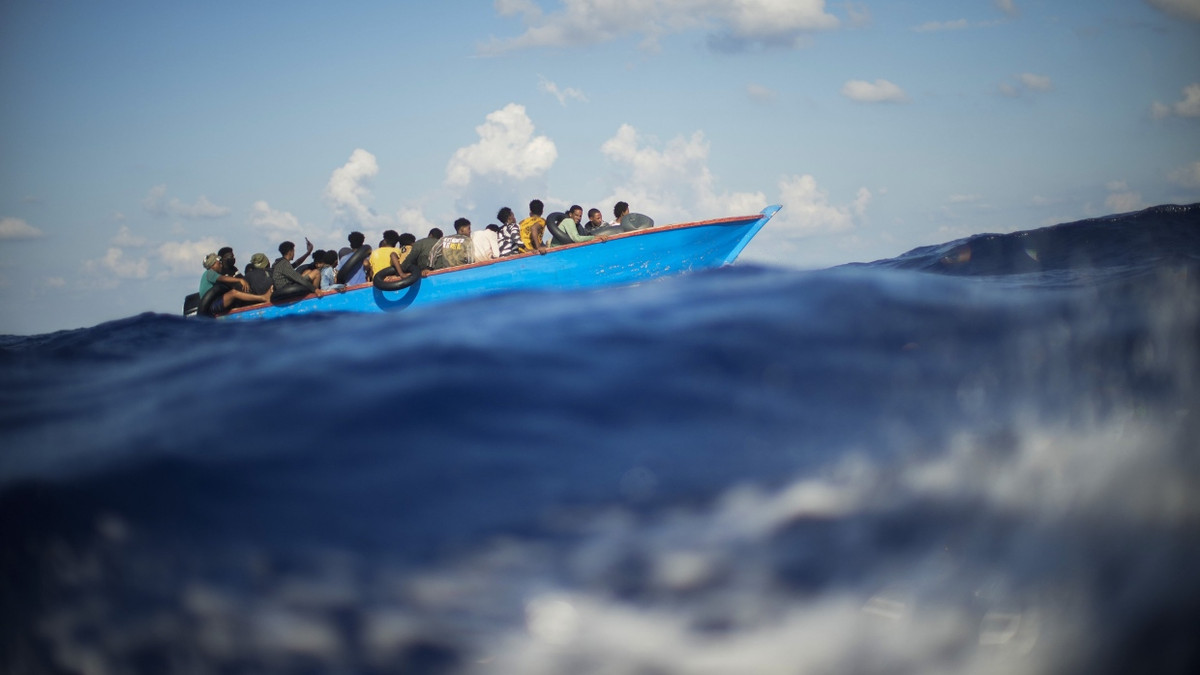 Migranten sitzen in einem Holzboot südlich der italienischen Insel Lampedusa auf dem Mittelmeer. - dpa