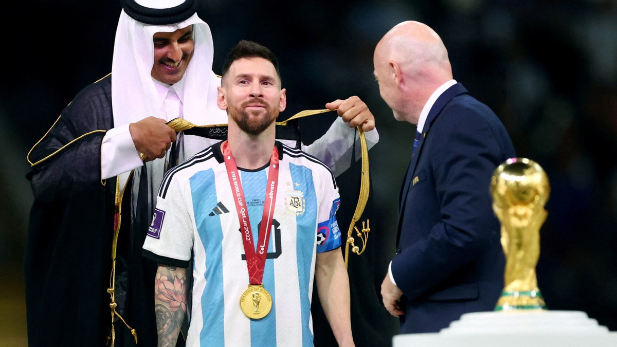 Vor den Augen der Welt: Der Emir von Qatar, Tamim bin Hamad Al Thani, hängt Weltmeister Lionel Messi ein qatarisches Gewand um. - Reuters