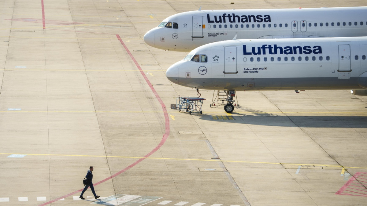 Ein Mann geht an zwei Lufthansamaschinen vorbei, die auf einer Freifläche vor einer Wartungshalle am Frankfurter Flughafen stehen - dpa