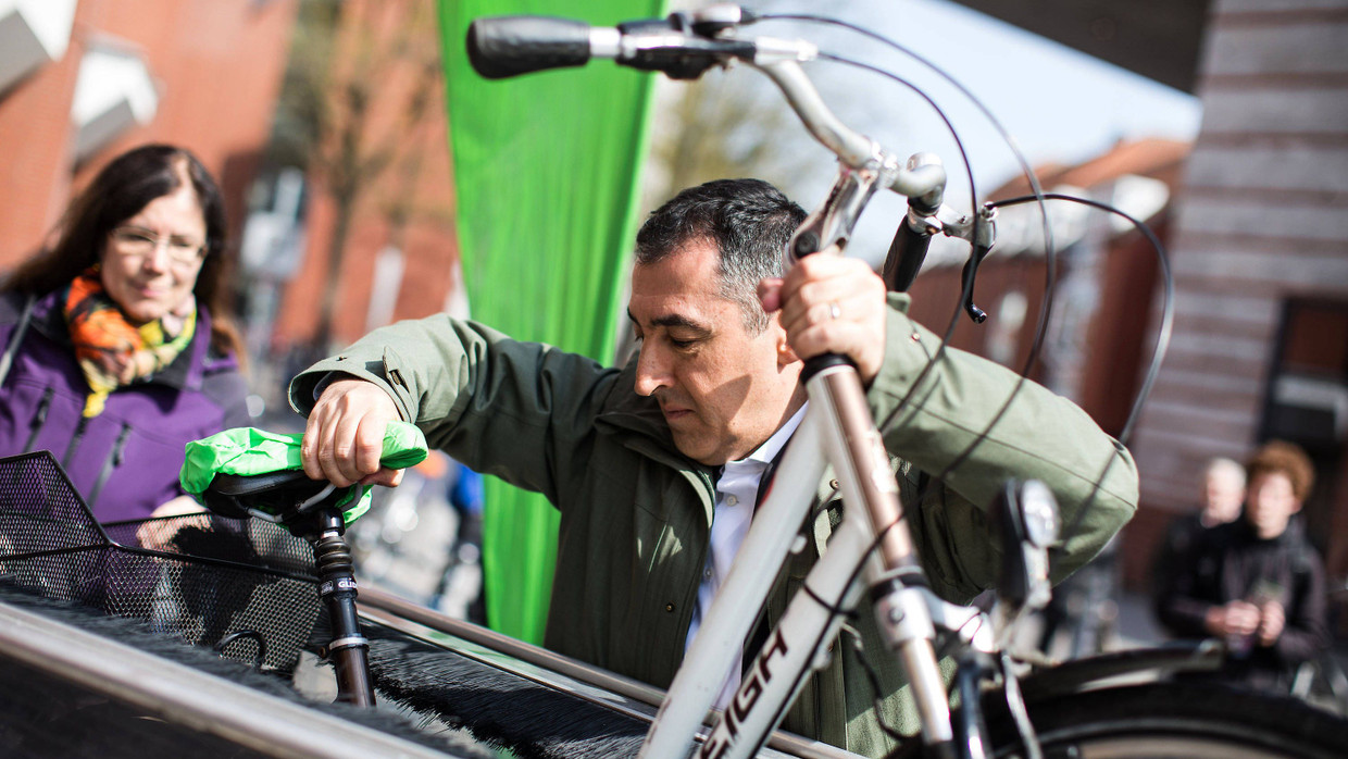 Cem Özdemir schiebt ein Fahrrad in eine automatische Fahrradwaschanlage.