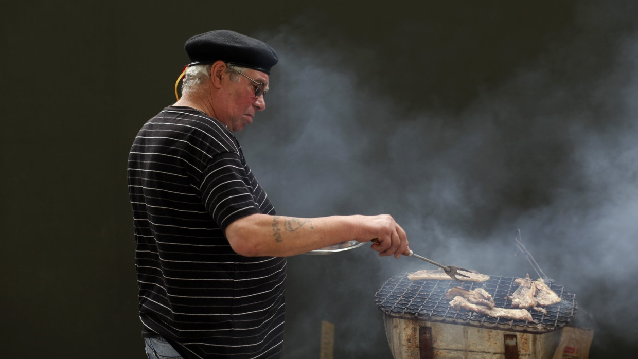 Ein Mann grillt am Tag der Arbeit in Lissabon Fleisch.