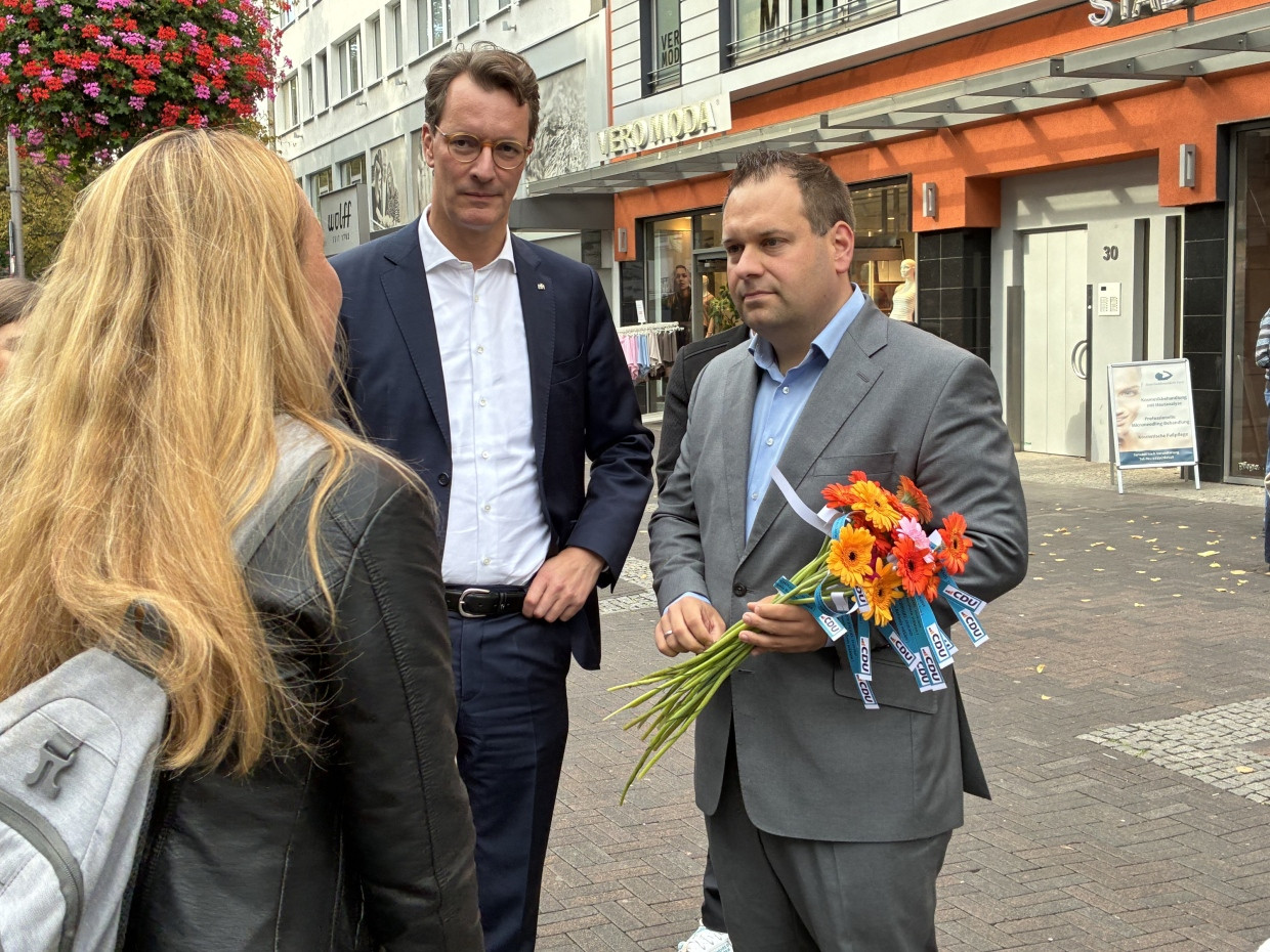 Ministerpräsident Hendrik Wüst und Dennis Rehbein (beide CDU) im Gespräch mit einer Frau in Hagen