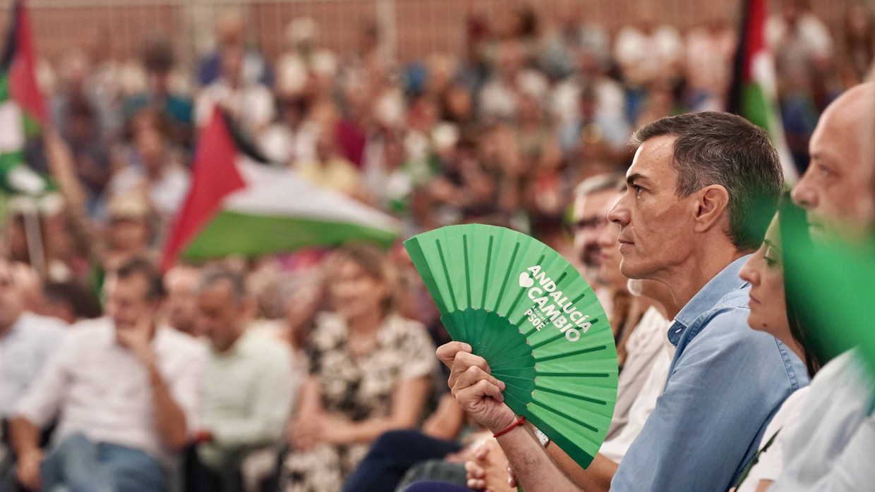 Pedro Sánchez auf einem Treffen seiner Partei PSOE, im Hintergrund schwenkt ein Teilnehmer die palästinensische Flagge.