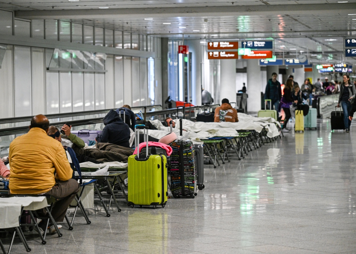 Menschen warten nach Drohnensichtungen und Flugausfällen in Flughafen München auf Feldbetten.