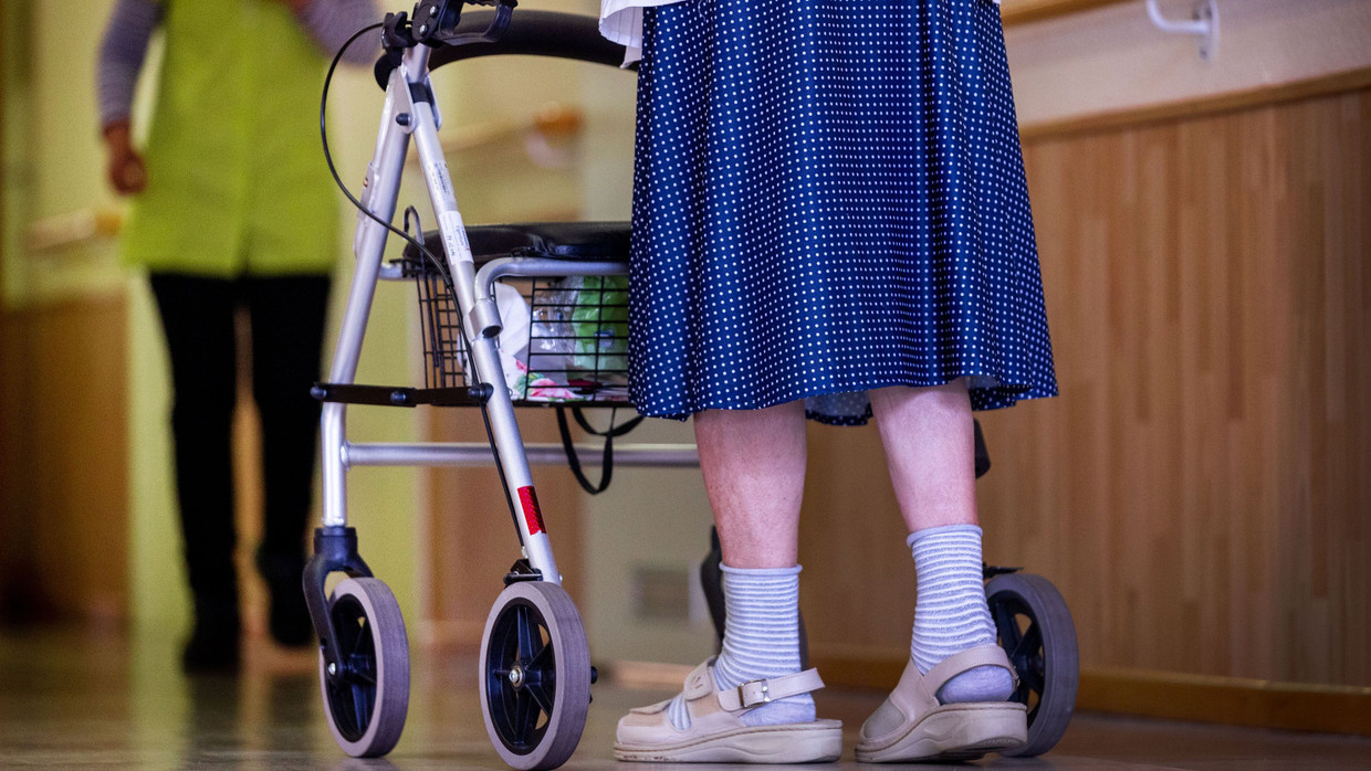 Eine ältere Dame geht in einem Pflegeheim in Mecklenburg-Vorpommern mit ihrem Rollator über einen Flur.