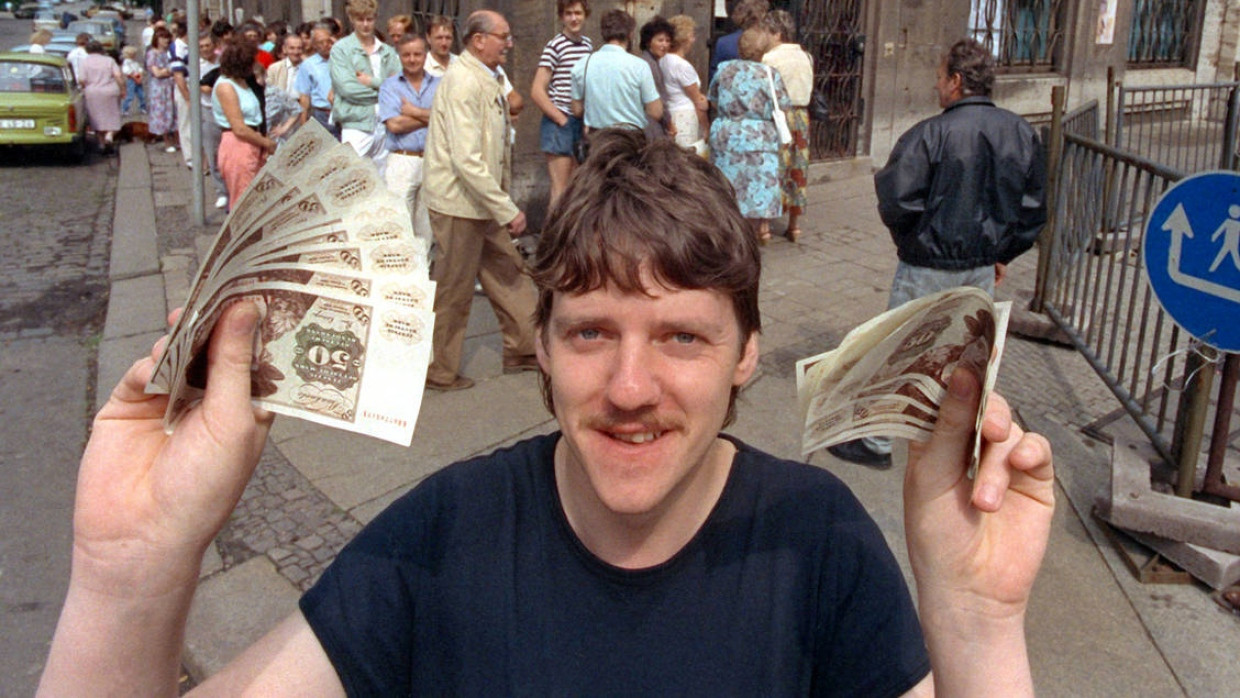 Für eine Hand voll D-Mark: Nach langem Schlangestehen vor einer Leipziger Bank freut sich ein junger Mann im Jahr 1990 über seine D-Mark-Banknoten.