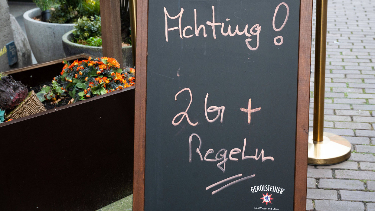 Ein Hinweisschild mit Aufschrift "Achtung! 2G+ Regel" steht vor einem Restaurant in der Innenstadt.