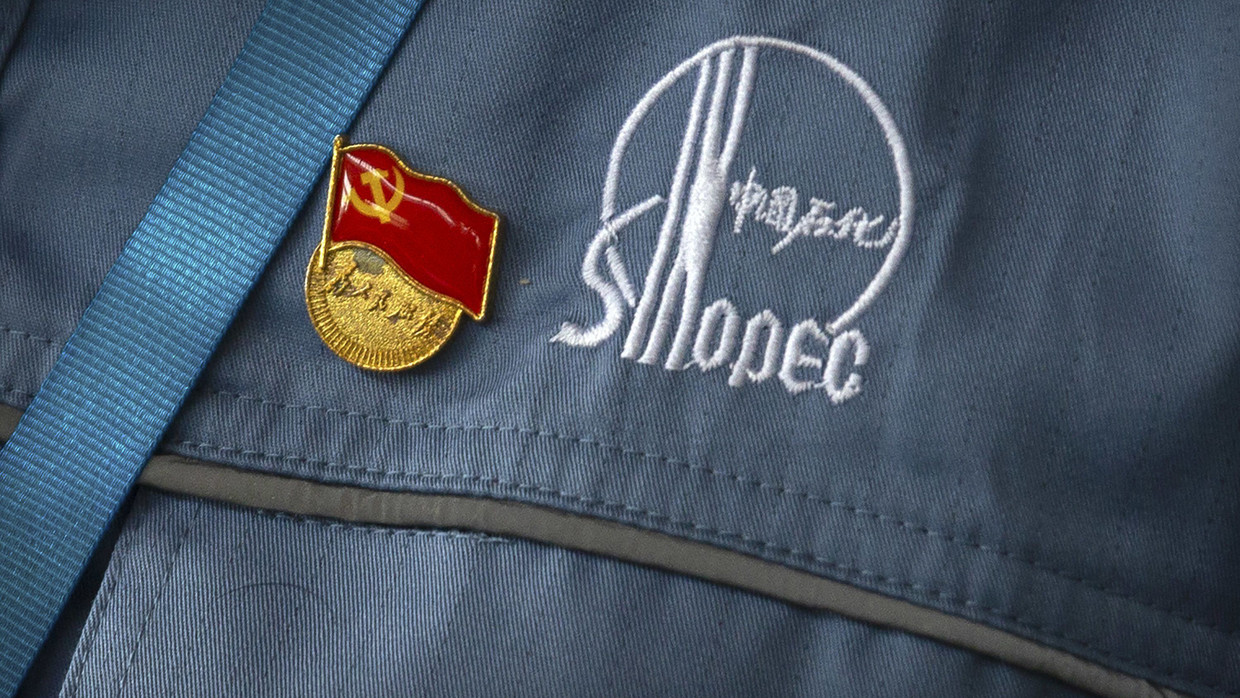 Ein kommunistisches Parteiabzeichen an der Uniform eines Sinopec-Arbeiters